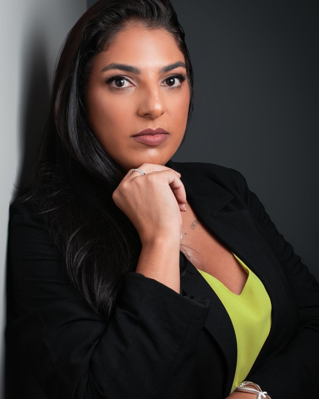 Paula, sócia da ID Marca, em retrato de estúdio com blazer preto e fundo escuro.